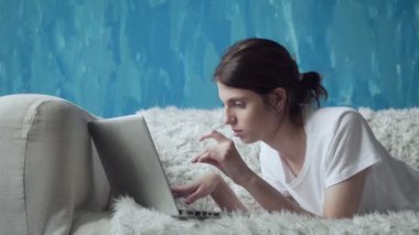 Dizüstü evde kanepede yatan süre kullanan kadın.