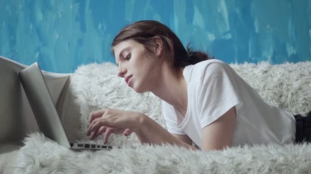Leende kvinna använder laptop hemma liggandes på soffan. — Stockvideo