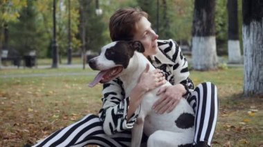 Kadın yerde oturan ve onu Stafford köpeği kucaklayan.