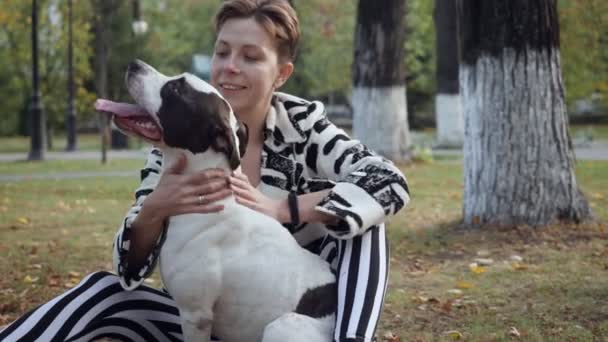 Kobieta siedzi na ziemi i obejmując jej pies Stafford. — Wideo stockowe