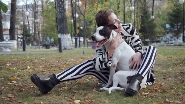 Женщина сидит на земле и обнимает свою стаффордскую собаку . — стоковое видео