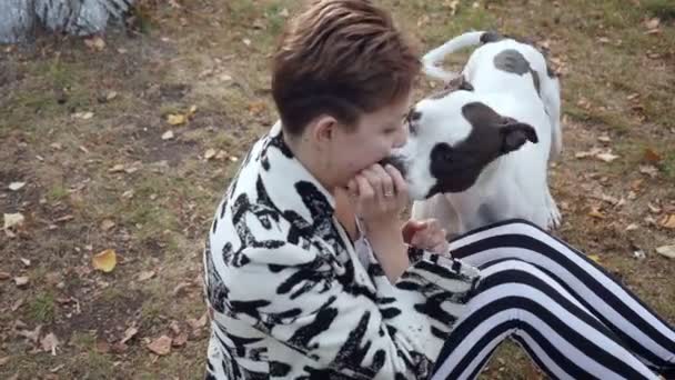 Kvinna som sitter på marken och omfamnar hennes Stafford hund. — Stockvideo