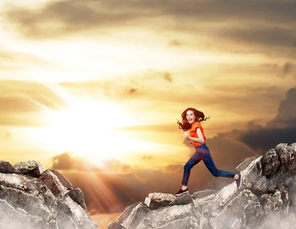 Redhead woman jumps over cliff on blue sky background. — Stock Photo, Image