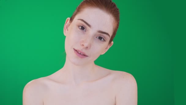 Femme rousse posant, souriant sur l’appareil-photo avec des épaules nues. — Video