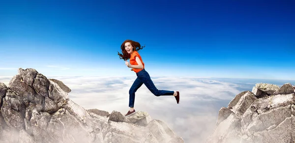 Руда жінка стрибає через скелю на фоні блакитного неба . — стокове фото