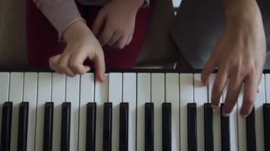 Elektrikli piyano çalan küçük kız ile öğretmen üst görünümü.