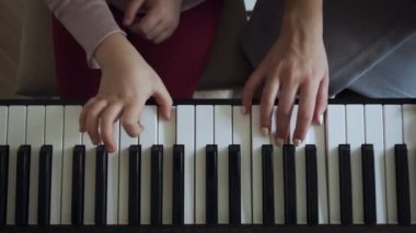 Elektrikli piyano çalan küçük kız ile öğretmen üst görünümü.