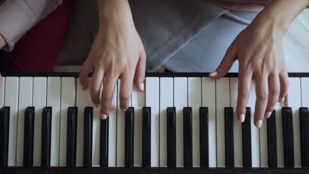 Top uitzicht op leraar met klein meisje spelen op de elektrische piano. — Stockvideo