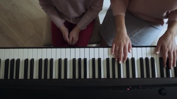Blick von oben auf Lehrer mit kleinem Mädchen, das auf dem E-Piano spielt. — Stockvideo