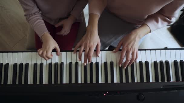 Top uitzicht op leraar met klein meisje spelen op de elektrische piano. — Stockvideo