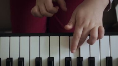 Elektrikli piyano çalan küçük kızın elleriyle üst tenli görünüm.