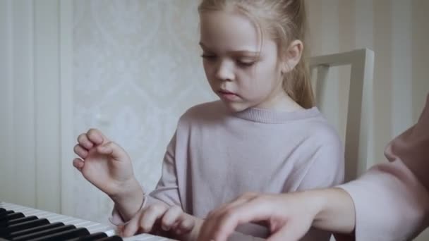 Genç öğretmen ve küçük tatlı kız elektrikli piyanoda oynuyorlar.. — Stok video