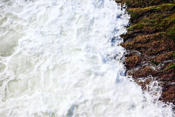 A onda do mar lava rochas torna-se espuma branca . — Fotografia de Stock