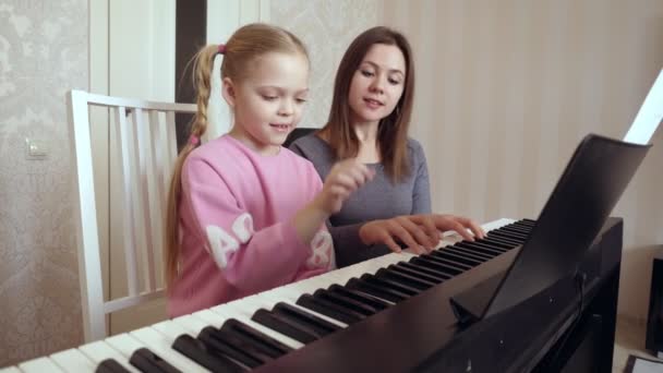 Giovane donna insegna bambina a suonare il pianoforte . — Video Stock