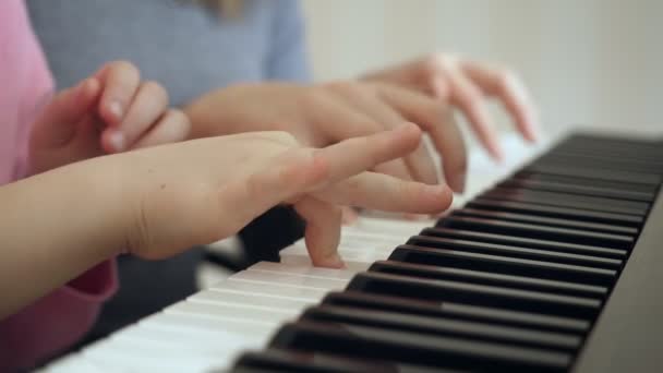Mladá žena učí holčičku hrát na klavír. — Stock video