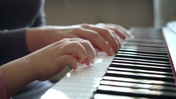 Young woman teaches little girl to play the piano. — Stock Video