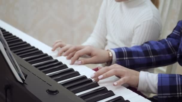Genç bir kadın küçük bir kıza piyano çalmayı öğretiyor.. — Stok video