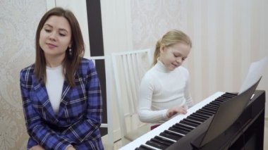 Küçük sevimli kız müzik öğretmeni için kulak kontrol eder.