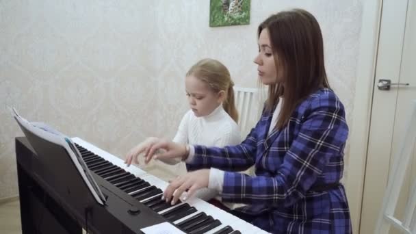 Young woman teaches little girl to play the piano. — Stock Video