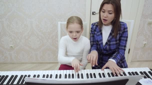 Jovem professora e menina tocando piano juntos . — Vídeo de Stock