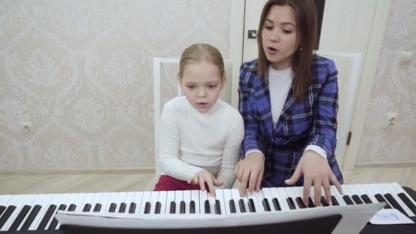 Ung kvinna lärare och liten flicka spelar piano tillsammans. — Stockvideo