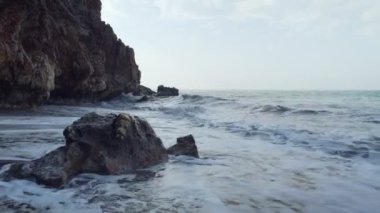 Huzursuz dalgalar mağara yakınındaki kayalarüzerinde yendi.