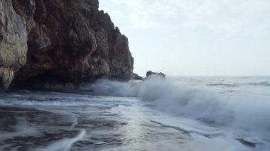 Huzursuz dalgalar mağara yakınındaki kayalarüzerinde yendi.