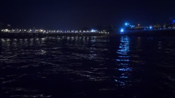 Nacht stadslichten reflecterend op de zee. — Stockvideo