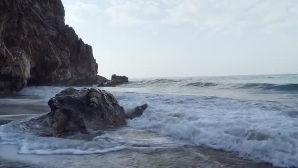 Nyugtalan hullámok verte a sziklák közelében barlang. — Stock videók
