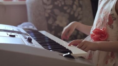 Tanınmayan küçük kız elektrikli piyano çalmak için okuyor.