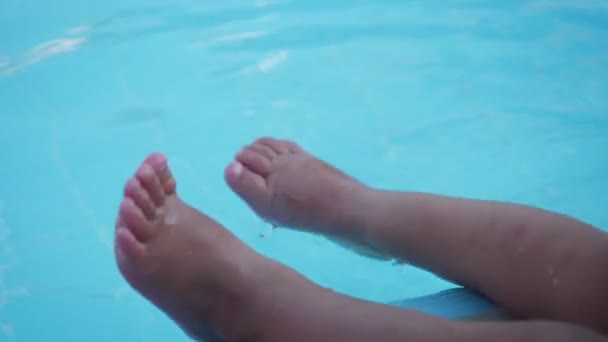 Ver en las piernas de niña jugando en la piscina de agua en el día de verano . — Vídeos de Stock