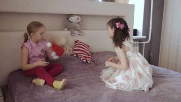 Dos niñas jugando juntas en la cama con juguetes de peluche . — Vídeo de stock