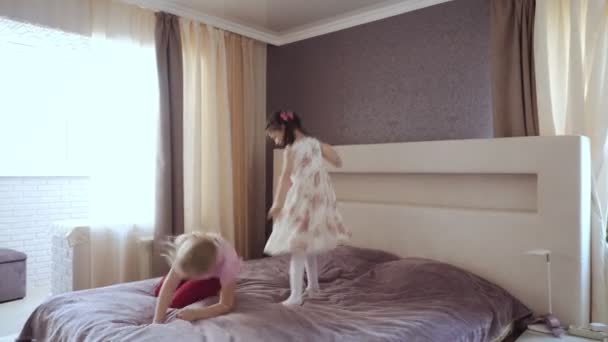 Две маленькие девочки прыгают на кровати . — стоковое видео