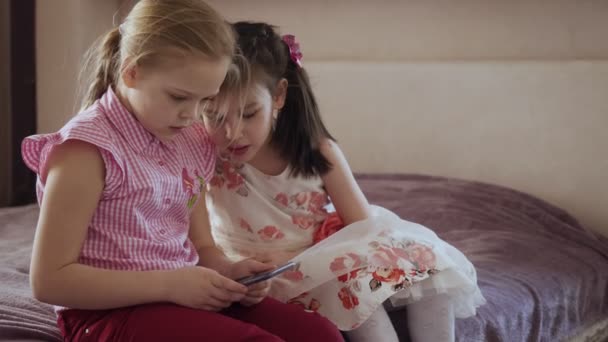 Duas meninas usando smartphone sentado na cama no quarto . — Vídeo de Stock