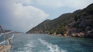Denizde yüzen tekneden Kekova harabeleri görünümü.