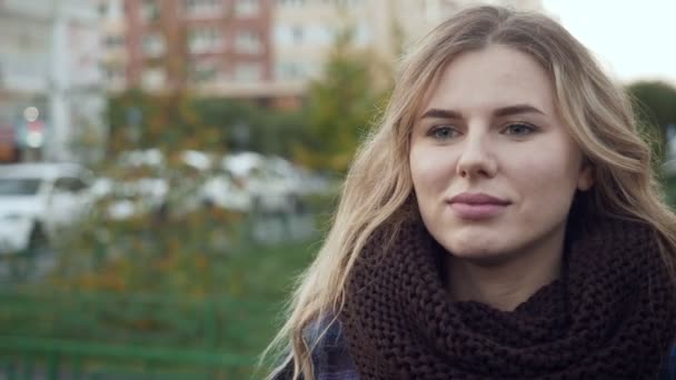 Gorgeous young blond woman in big knit scarf outdoors. — Stock Video