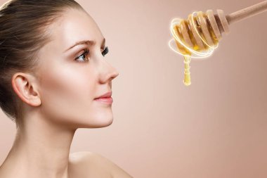 Genç kadın bal ile kaşık bakar ve yüz maskesi için hazırlamak.