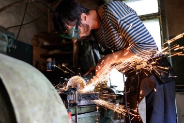 Profesyonel demirci demirhanede el dairesel testere ile metal testere.