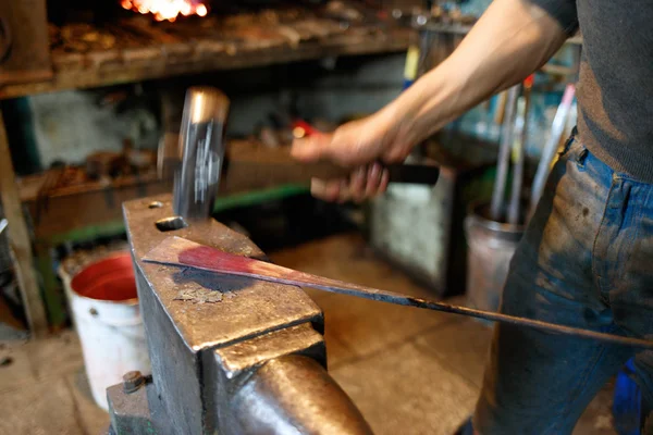 Herrero forjando metal rojo-caliente con martillo . — Foto de Stock