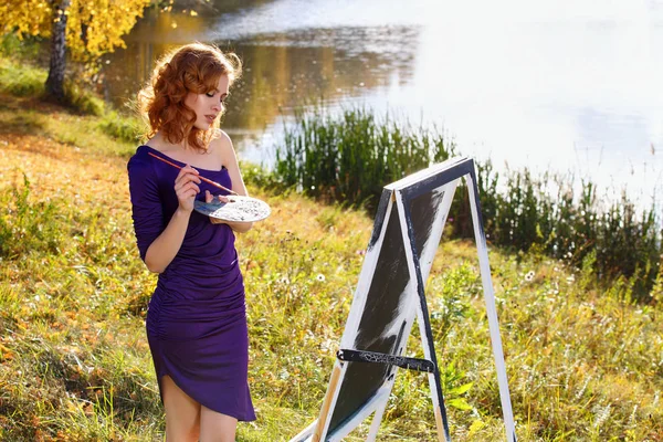 Jeune femme en robe sexy peinture en plein air dans le parc d'automne . — Photo