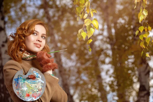 秋の公園でパレットとブラシでポーズをとる若い女性. — ストック写真