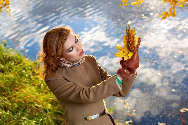 Giovane donna nel parco e tiene giallo autunno foglie d'acero . — Foto Stock