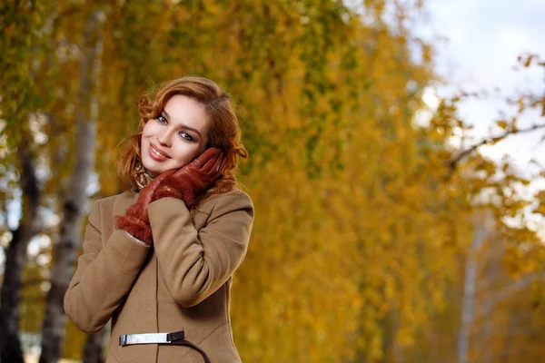 Mulher elegante em casaco bege e luvas de pé no outono parque amarelo . — Fotografia de Stock