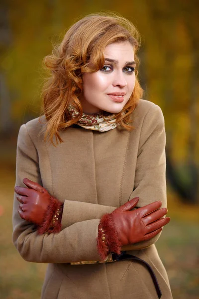 Stylische Frau in beigem Mantel und Handschuhen im herbstgelben Park. — Stockfoto