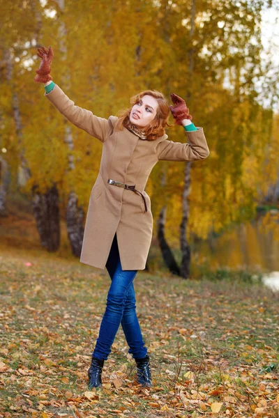 Stylová žena v béžovém kabátě a rukavice stojící na podzimní žluté partě. — Stock fotografie