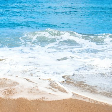 Kumlu plaj ve whie köpük ile yumuşak mavi okyanus dalgası.