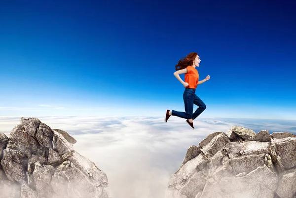 Redhead woman jumps through the gap between hills. — Stock Photo, Image