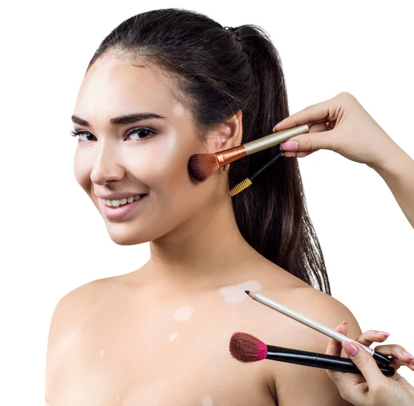 Young woman with vitilio among hands with make-up brushes. — Stock Photo, Image