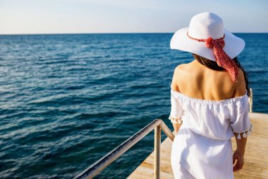 Ahşap iskele üzerinde yürüyüş beyaz yaz elbise kadın arka görünüm.