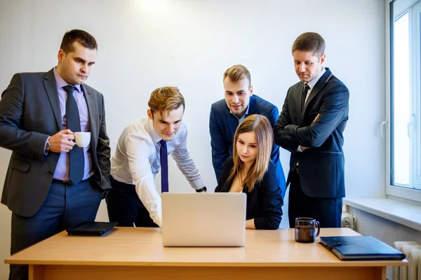 Woman sitting at the desk, the team is standing around her. — Stock Photo, Image